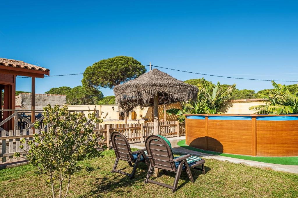 a backyard with two chairs and a table and a gazebo at Las tres hermanas in Conil de la Frontera