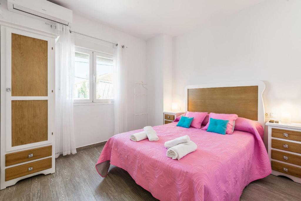 sypialnia z różowym łóżkiem z 2 poduszkami w obiekcie Apartamento La Higuera 3 w mieście Conil de la Frontera