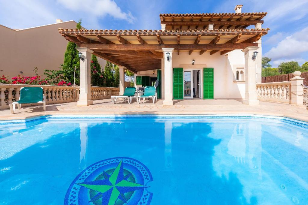 a swimming pool in front of a house with a pergola at Can Mateu in Cala Santanyi