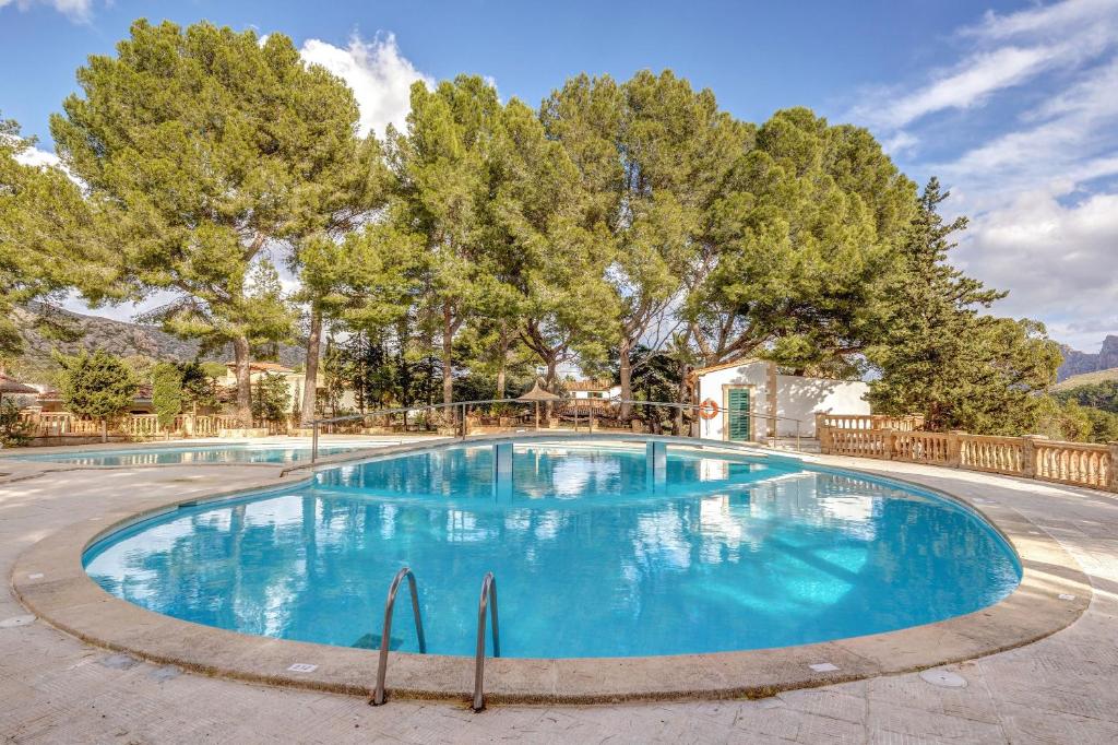 a large blue swimming pool with trees in the background at Villa Gran Voramar in Cala de Sant Vicent