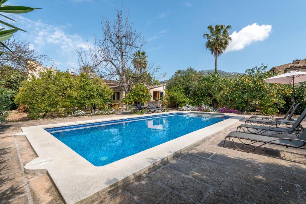 a swimming pool with two chairs and an umbrella at Finca Ca'n Vaqueta in Sóller