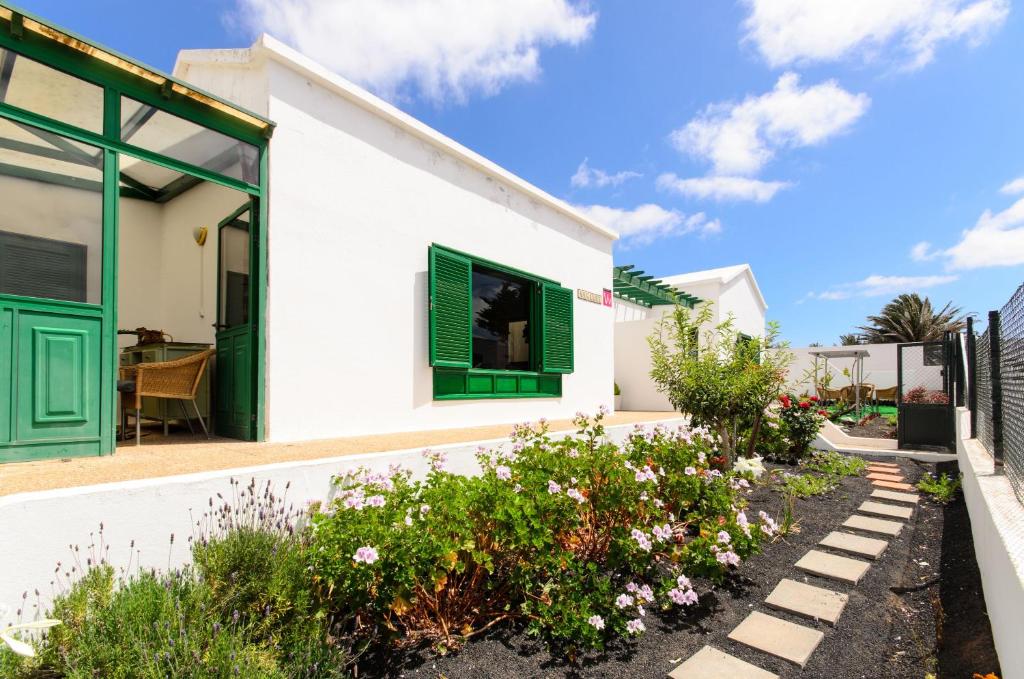 a white house with green shutters and flowers at Casa Angeles 1 in Tao