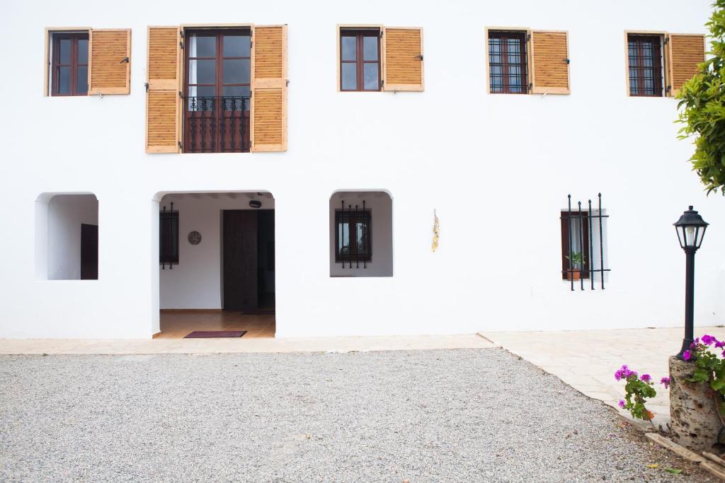 Un edificio blanco con ventanas y una entrada para coches. en Can Murenu, en Sant Joan de Labritja