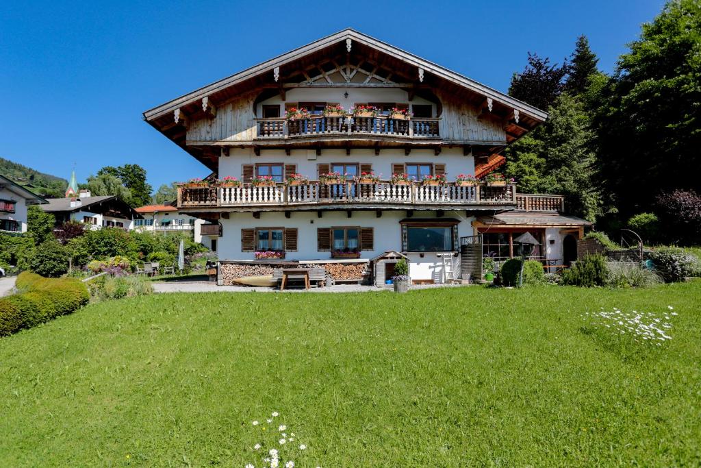 ein großes Haus mit einem Balkon und einem Grasfeld in der Unterkunft Ferienwohnung Landhaus Staudacher in Tegernsee