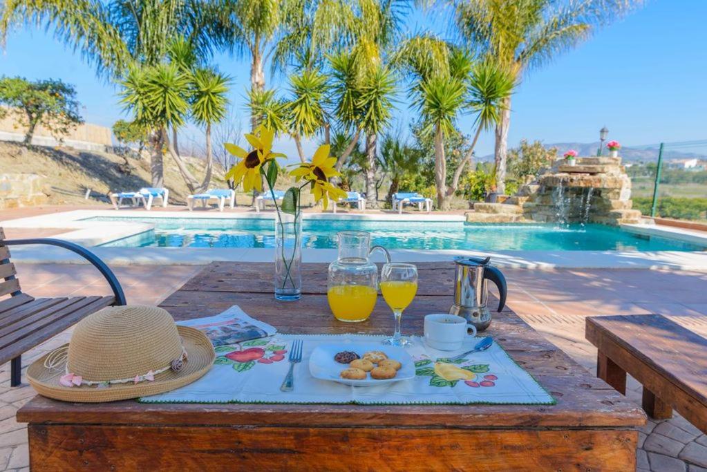 uma mesa com uma bandeja de comida e copos de sumo de laranja em Villa Quilin em Alhaurín el Grande