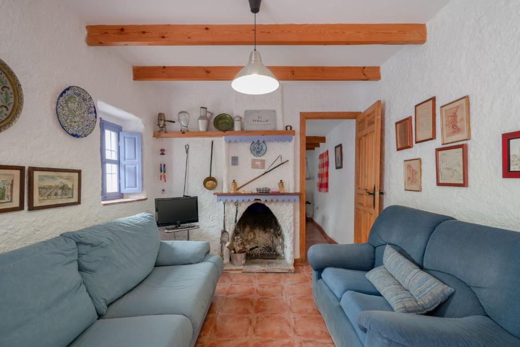 a living room with blue couches and a fireplace at Casa Rural El Tesillo in Canillas de Aceituno