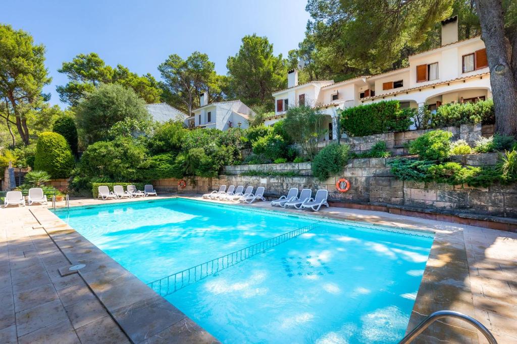 einen Pool mit Stühlen und ein Gebäude in der Unterkunft Can Botana 1 in Cala de Sant Vicent