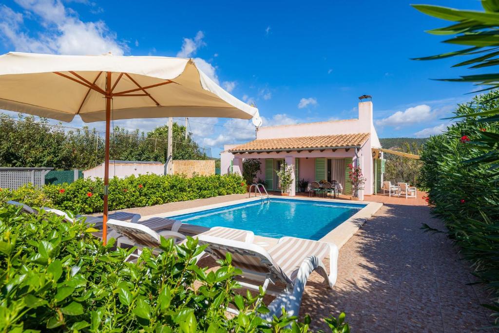 ein Pool mit Stühlen und einem Sonnenschirm und ein Haus in der Unterkunft Sa caseta de la Mar in Son Servera