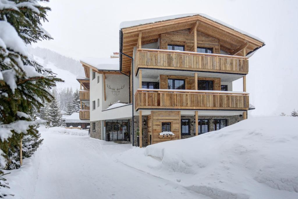 ein Holzhaus im Schnee mit einer verschneiten Straße in der Unterkunft Kösslerhof in Sankt Anton am Arlberg