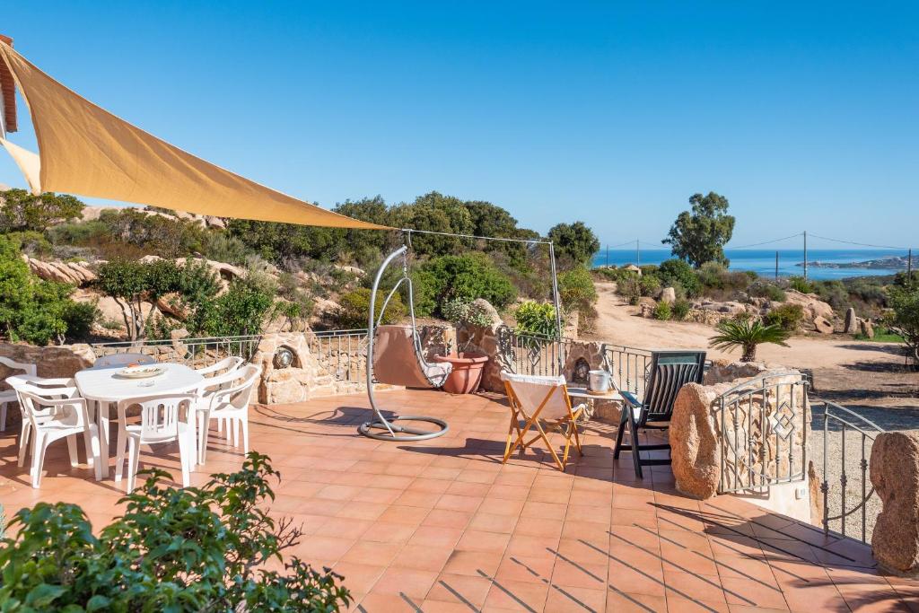 a patio with a table and chairs and a view of the ocean at Sun House Appartamento Vista Mare in Cannigione