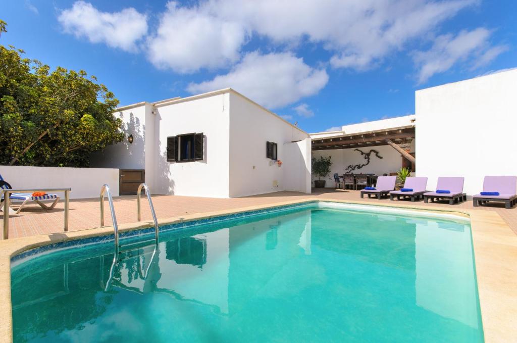 a villa with a swimming pool in front of a house at Finca La Rubina in Teguise