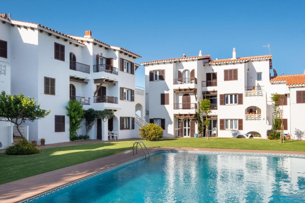 a villa with a swimming pool in front of two buildings at La Gardenia 41 in Es Castell