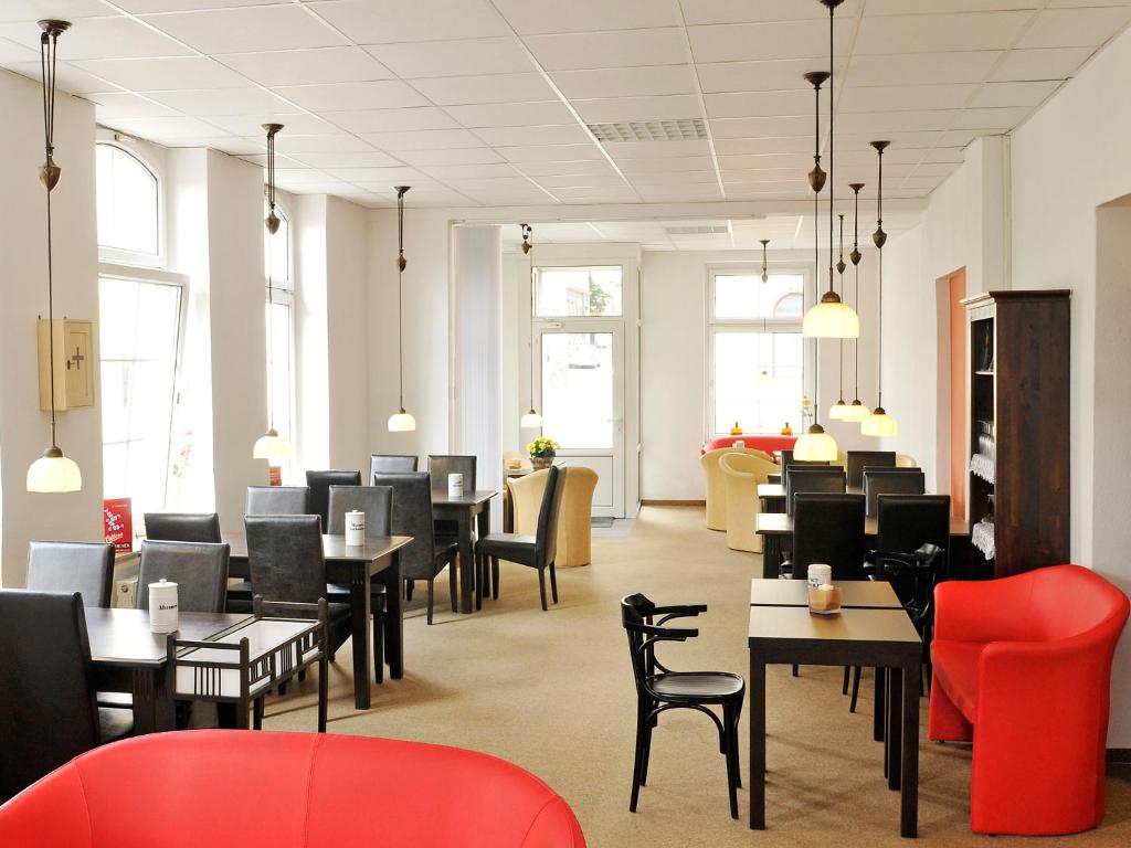 um restaurante com mesas pretas e cadeiras vermelhas em Pension Müllers Alte Backstube em Reichenbach im Vogtland