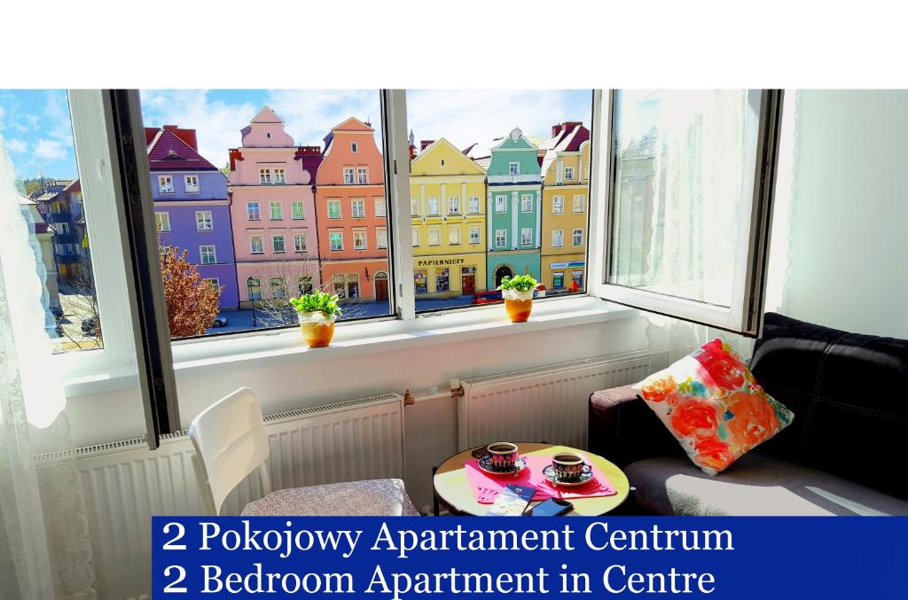 een kamer met twee ramen en een tafel aan de voorkant bij Apartament Przy Starówce - Stella in Bolesławiec