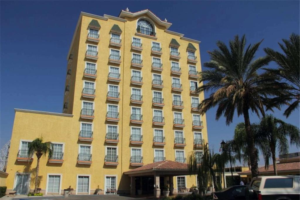 un gran edificio amarillo con palmeras delante en Best Western Hotel Posada Del Rio Express en Torreón