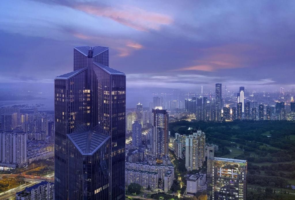 un rascacielos alto en una gran ciudad por la noche en Park Hyatt Shenzhen, an urban oasis in the heart of Futian CBD, adjacent to the Convention and Exhibition Center, Futian Port and Futian Railway Station, provides an artistic retreat, a home away from home, en Shenzhen