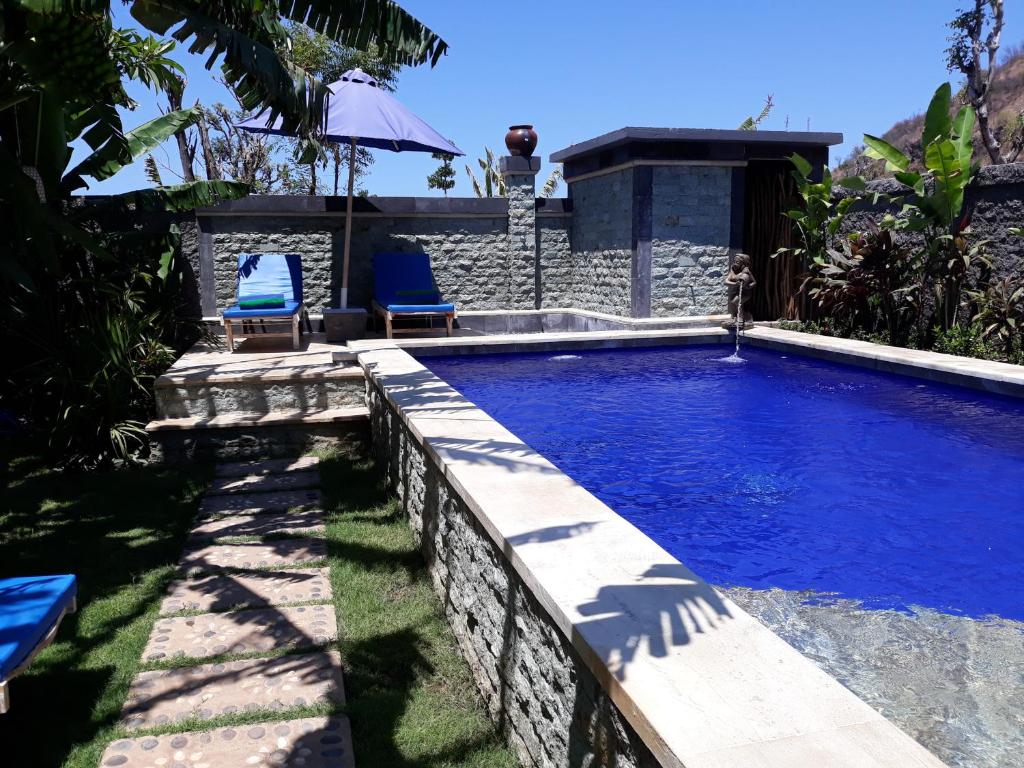 una piscina en un patio trasero con 2 sillas azules en Amed Sudi House, en Amed