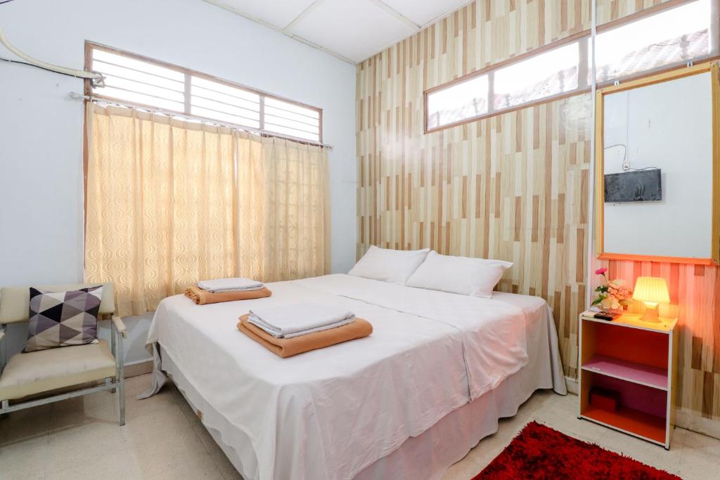 a bedroom with a bed and a chair and a window at Adil Jaya Homestay in Yogyakarta