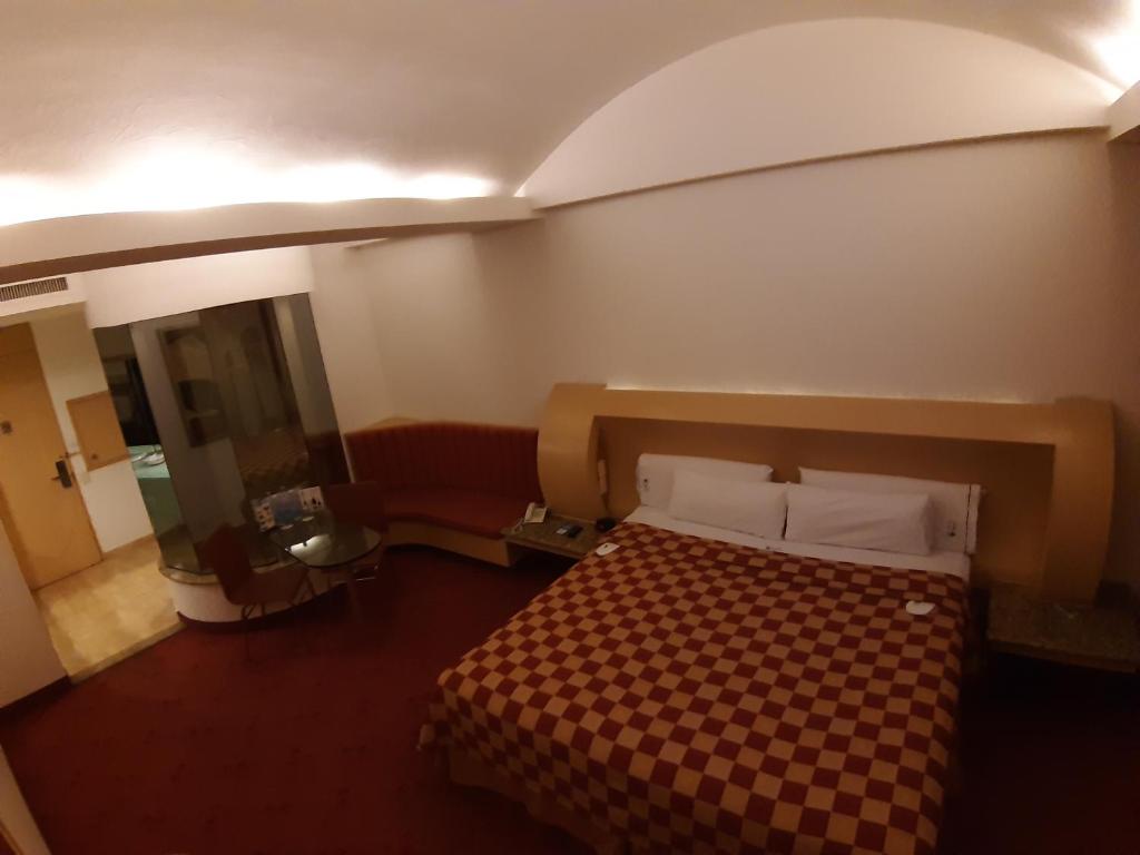 A one-bed room with a curved ceiling, upholstered seating area and mirrored dressing table.