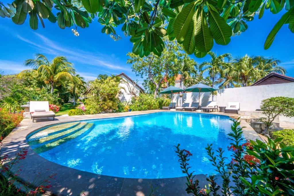 a swimming pool in the backyard of a house with trees at Ocean Sun Dive Resort in Tulamben