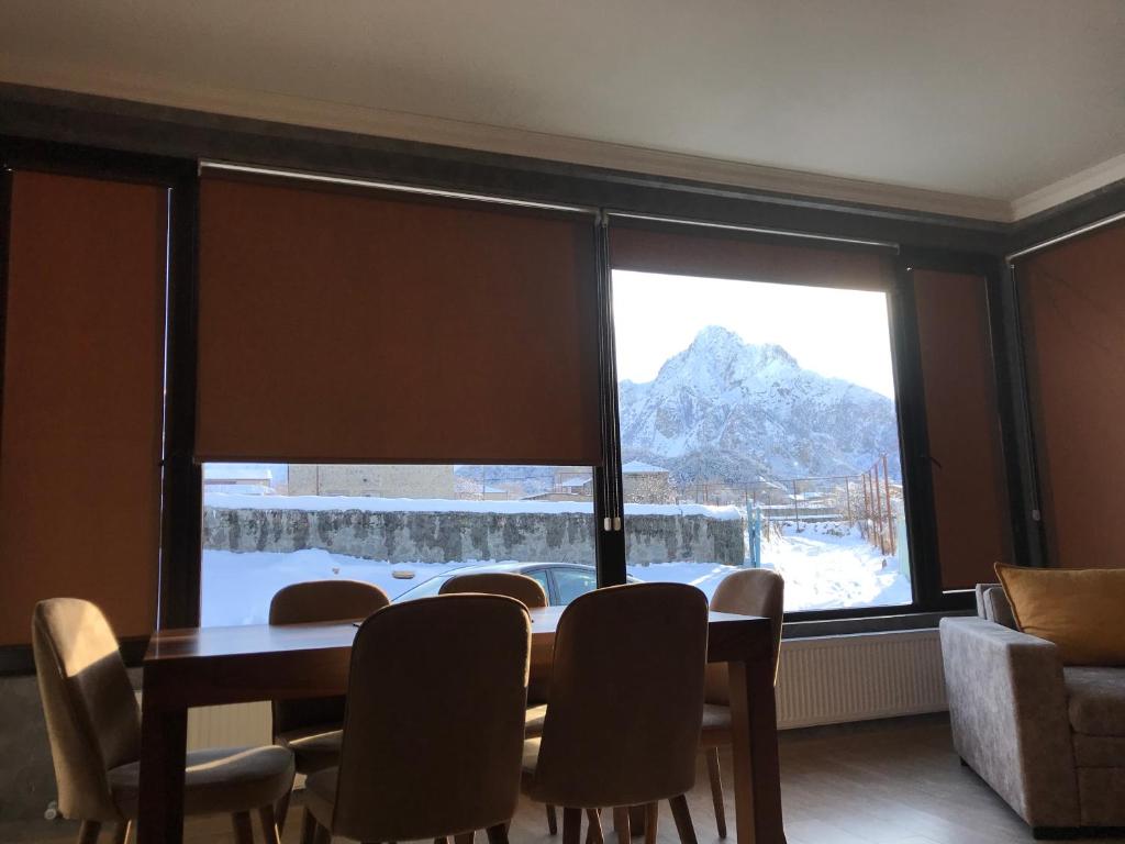 a dining room with a table and a large window at Green Apartment in Kazbegi