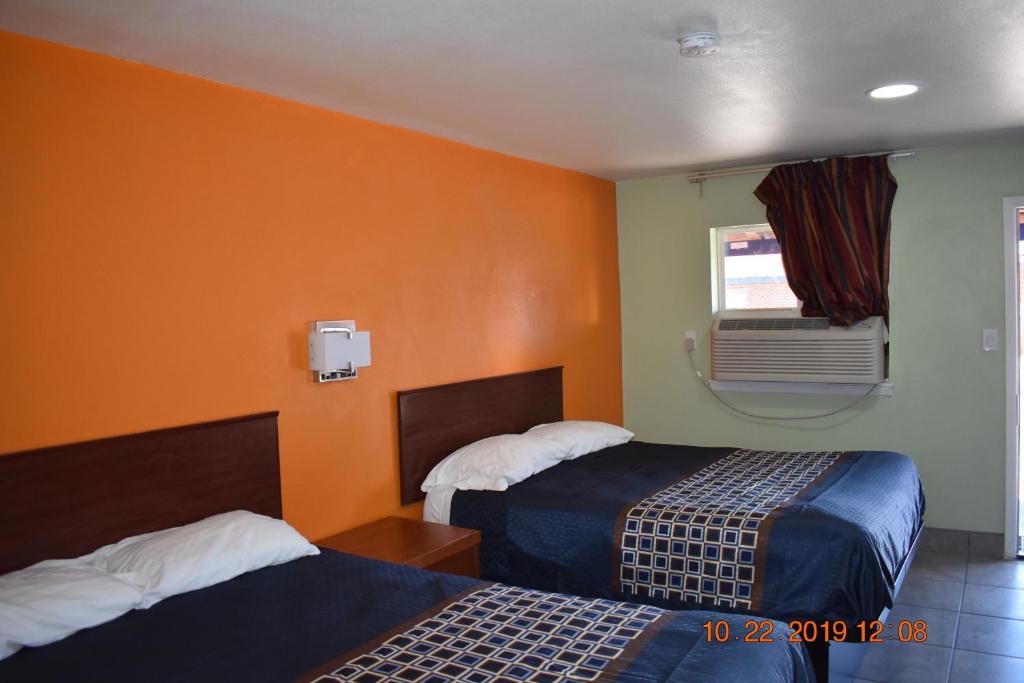 a hotel room with two beds and a window at Belmont Motel in Roswell