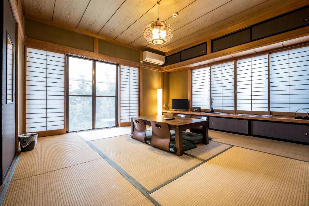 a room with a table and chairs and windows at Classic Japan Living ASAMA in Fujikawaguchiko