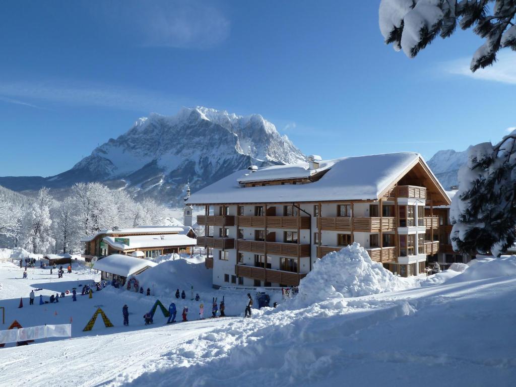 a snow covered building in front of a mountain at Apart Ideal in Lermoos