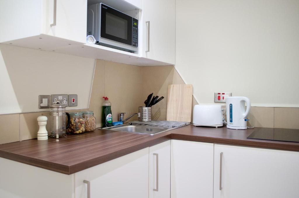 a kitchen with a stove top oven and a microwave at Palmerston Suites in Edinburgh