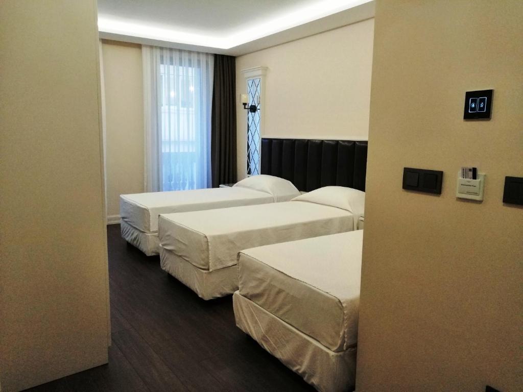 a hotel room with three beds and a window at MORAVA HOTEL in Istanbul