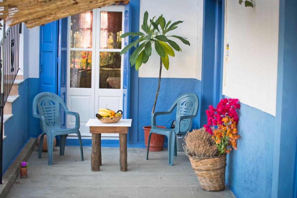 a blue house with two chairs and a table and flowers at Petroula Apartments in Emborios Kalymnos