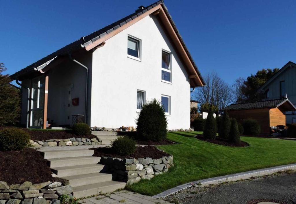 a white house with a stone wall at Ferienhaus - Haus Winterberg in Winterberg