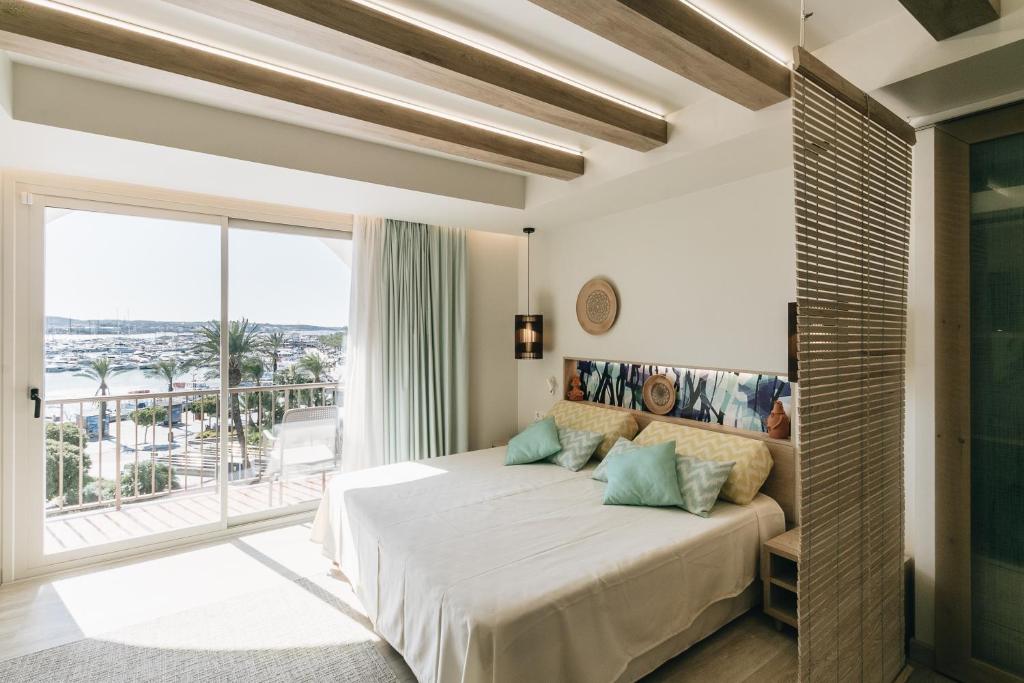 - une chambre avec un grand lit et une grande fenêtre dans l'établissement The White Apartments, à Sant Antoni de Portmany