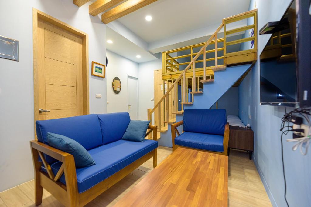 sala de estar con sofá azul y escaleras en 夏海民宿 en Magong