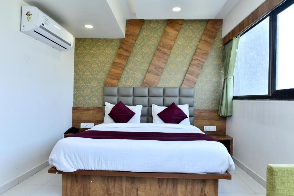 a bedroom with a large bed with red pillows at Hotel Royal King by Sky Stays in Ahmedabad