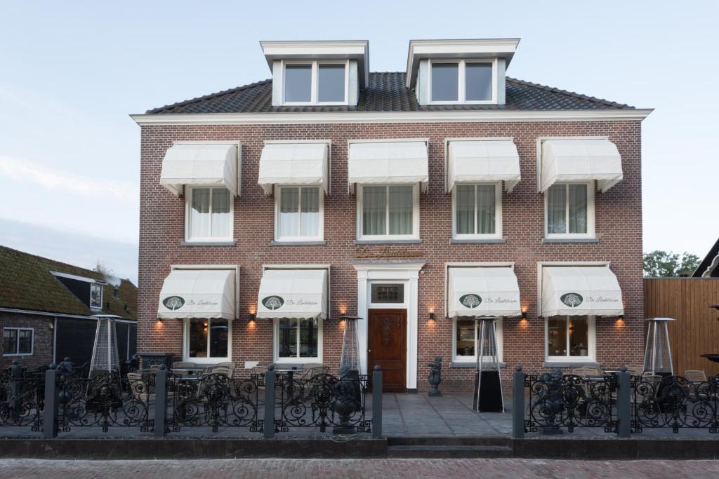 a brick building with white awnings on it at B&B - Brasserie De Lindeboom in Serooskerke