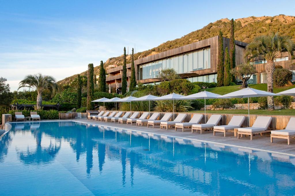 a hotel swimming pool with lounge chairs and umbrellas at Casadelmar in Porto-Vecchio