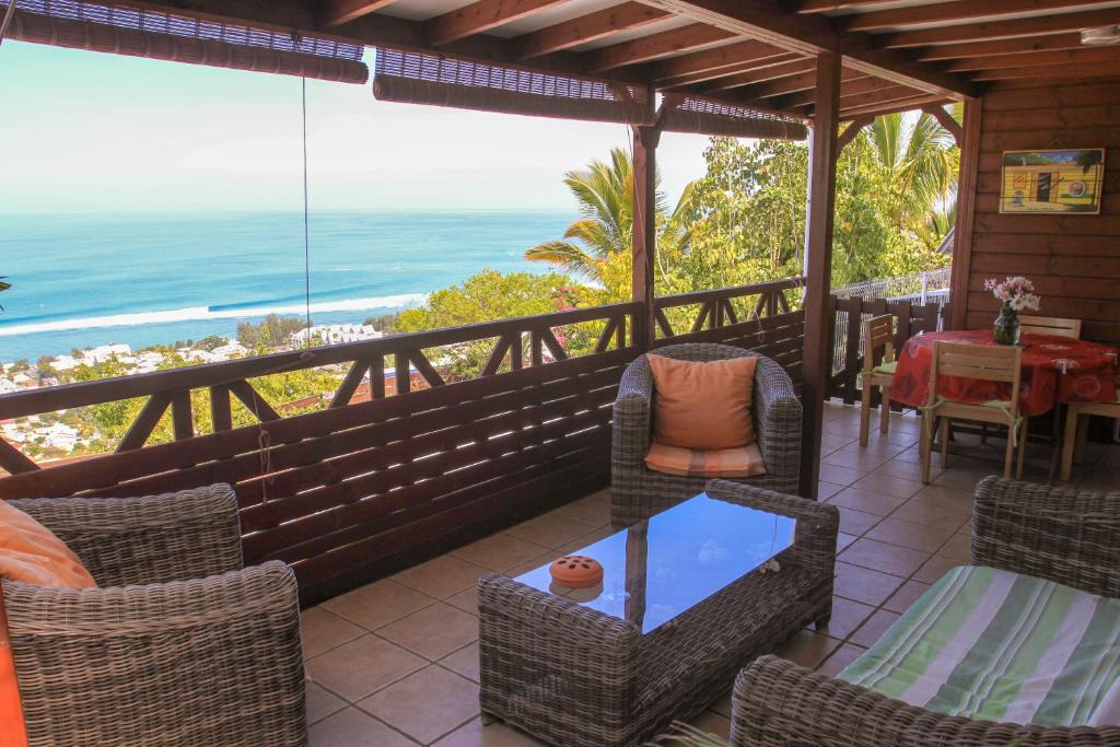 - une terrasse couverte avec des chaises et une table offrant une vue sur l'océan dans l'établissement Maison à Saint-Leu, vue panoramique sur l'océan à 2 minutes des plages, à Saint-Leu