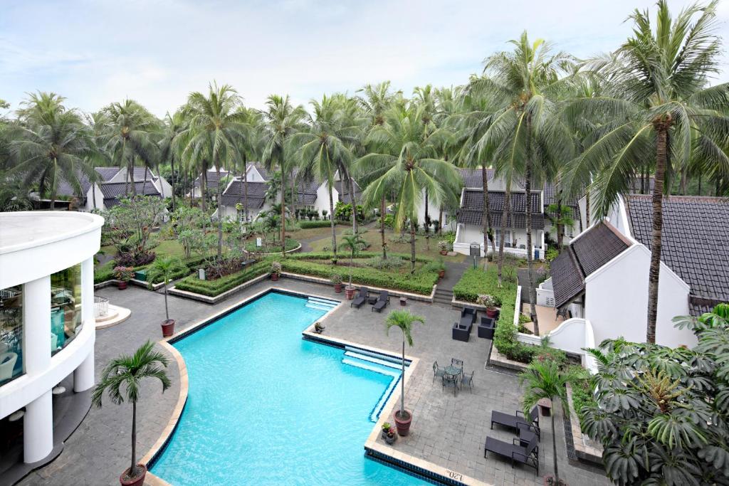 an aerial view of a resort swimming pool with palm trees at Aryaduta Lippo Village in Tangerang