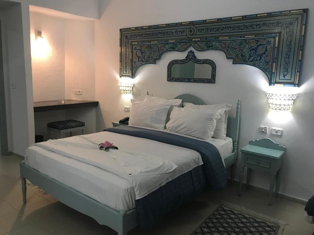 a bedroom with a large bed with a large headboard at Hotel Khella in Hammamet