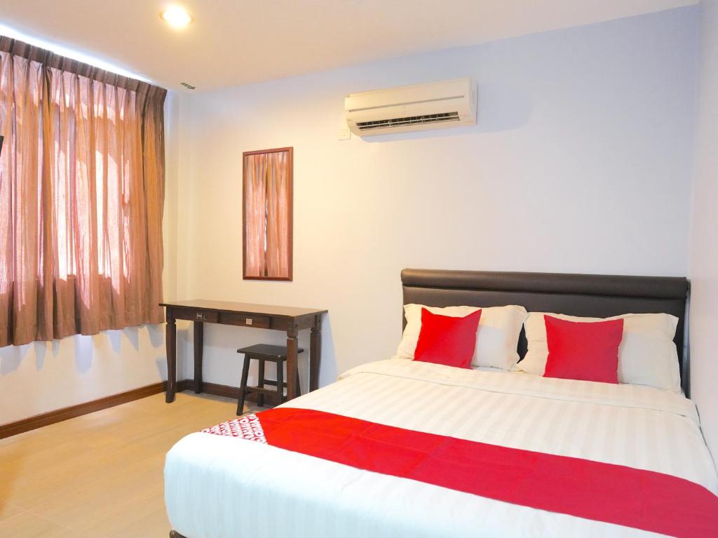 a bedroom with a bed with red pillows and a desk at Super OYO 89544 Utama Inn in Bintulu
