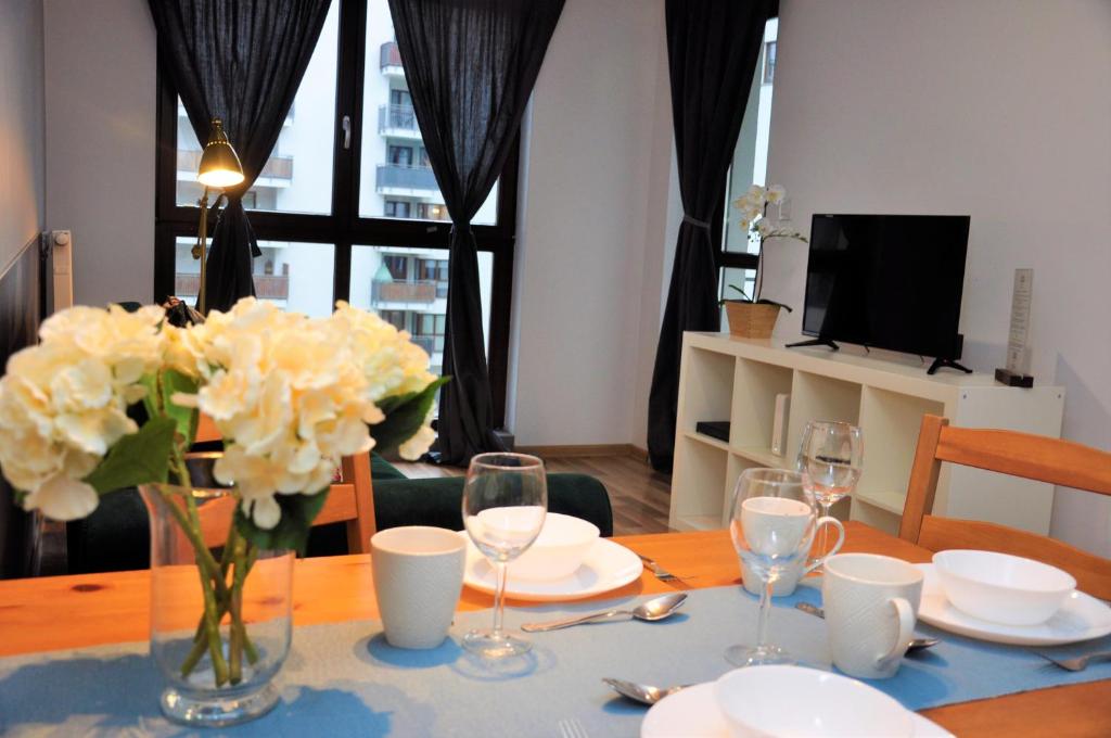 a dining room table with a vase of flowers on it at Prudentia Apartments Jana Kazimierza in Warsaw