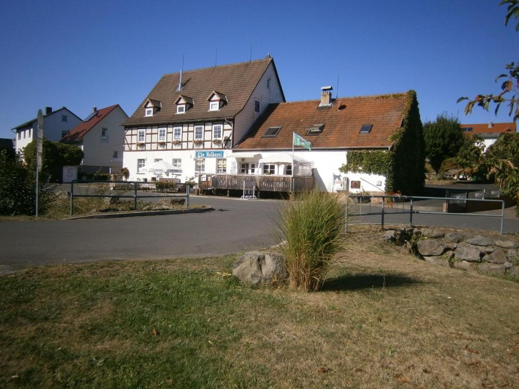 ein großes weißes Gebäude mit einem Haus in der Unterkunft Ferienwohnung An der Schlier in Neuental