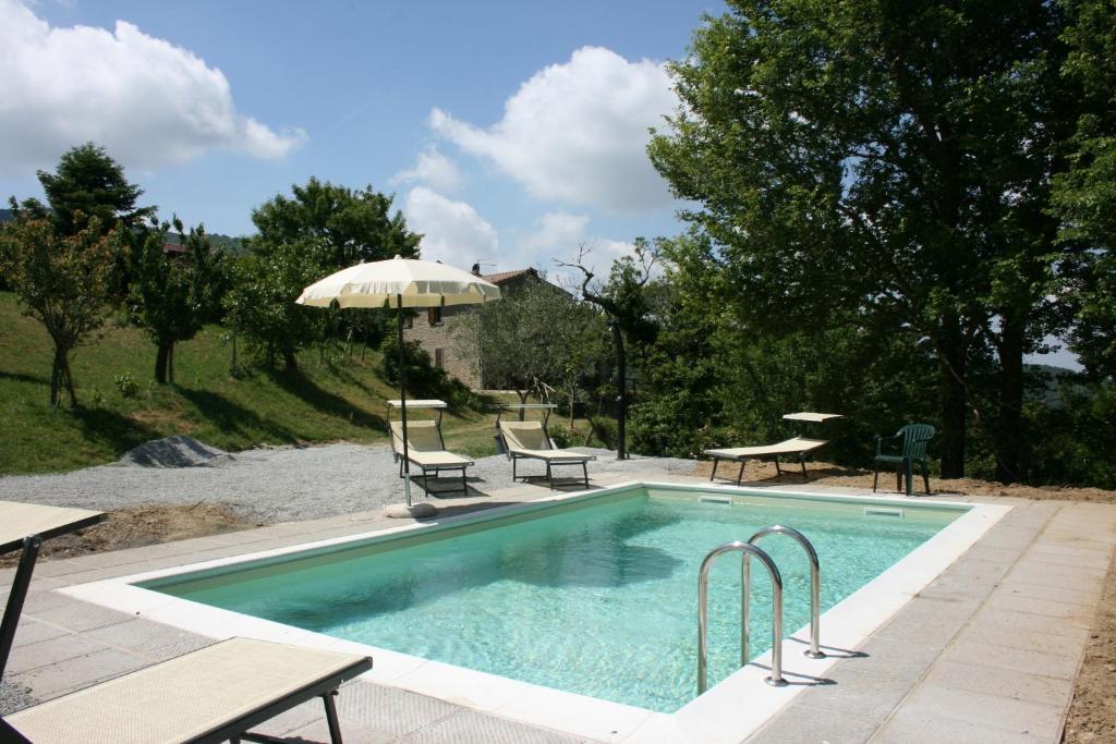 una piscina con due sedie e un ombrellone di Casetta i Ciliegi a Cortona