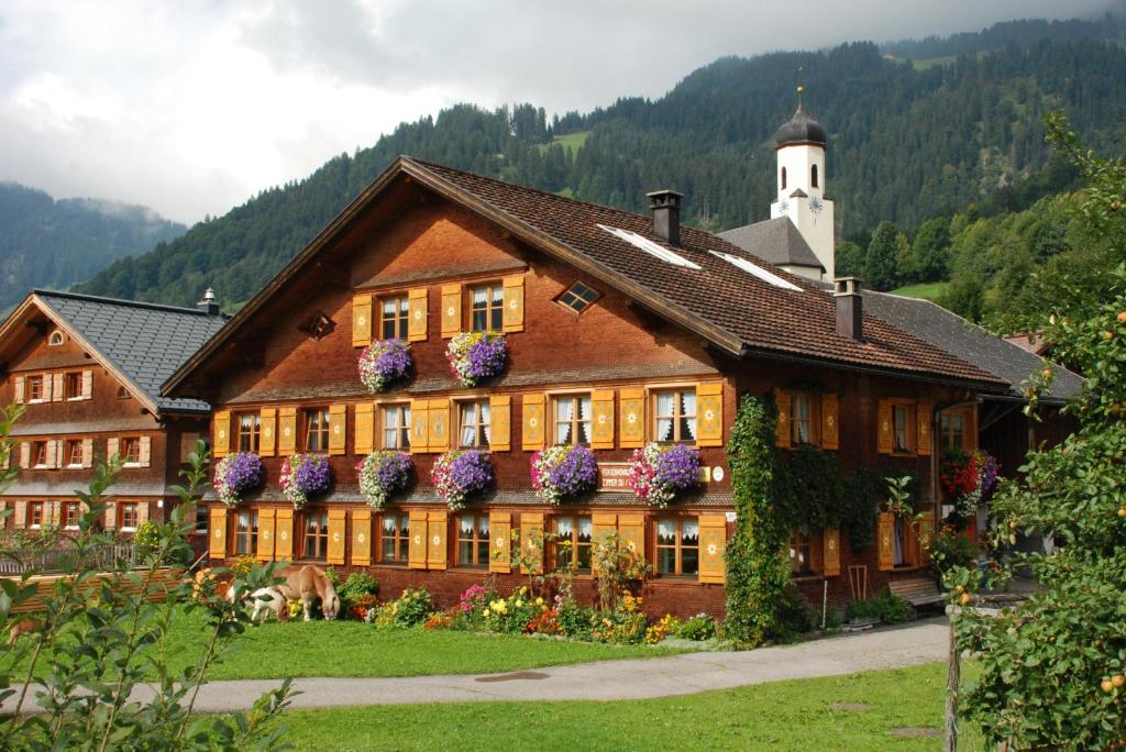 un bâtiment avec des fleurs sur son côté dans l'établissement Kinderbauernhof, à Schoppernau