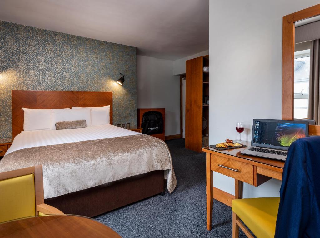 a hotel room with a bed and a desk with a laptop at Treacy’s Hotel Spa & Leisure Club Waterford in Waterford