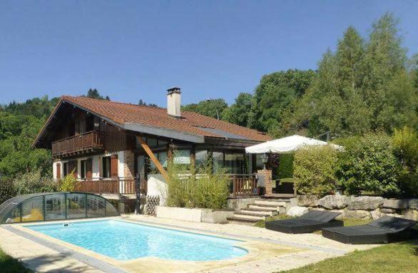 a house with a swimming pool in front of a house at Le chalet des Pesettes in Thorens-Glières