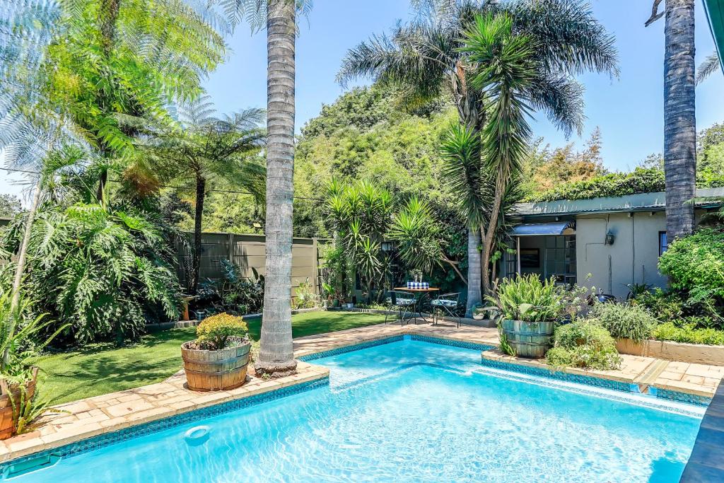 a swimming pool in a yard with palm trees at Seven Palms - Tranquility on Dover in Johannesburg