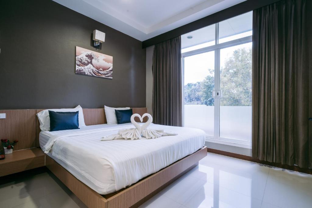 a bedroom with a large bed with a large window at Jintana Resort in Buriram