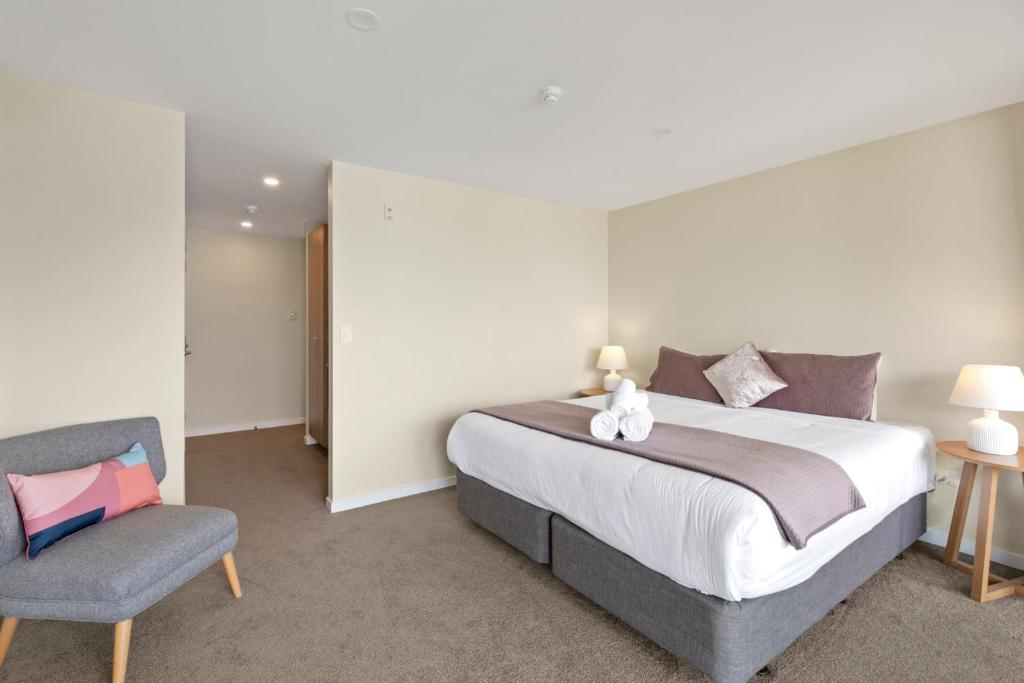 ein Schlafzimmer mit einem großen Bett und einem Stuhl in der Unterkunft Falcon&#39;s View Queenstown in Queenstown